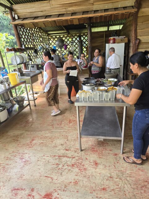 a group of women preparing food in an open air kitchen